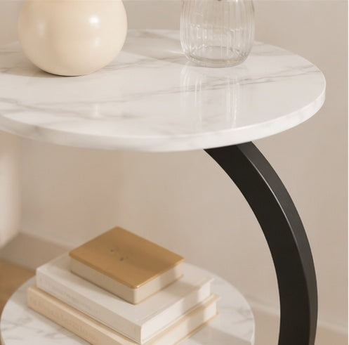 Gros plan sur le plateau en marbre blanc veiné et le pied noir arrondi de la table Calacata