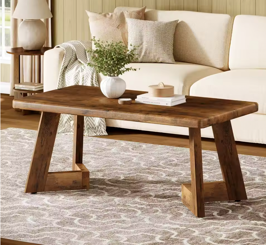 Table basse Farland style farmhouse en bois brut dans un salon avec plaid et plante