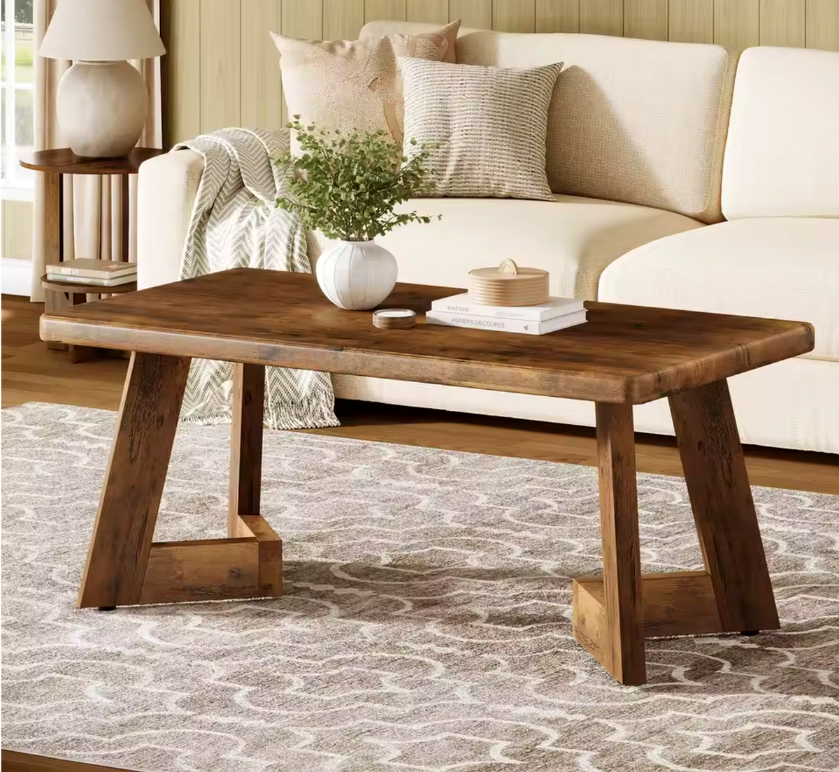Table basse Farland style farmhouse en bois brut dans un salon avec plaid et plante